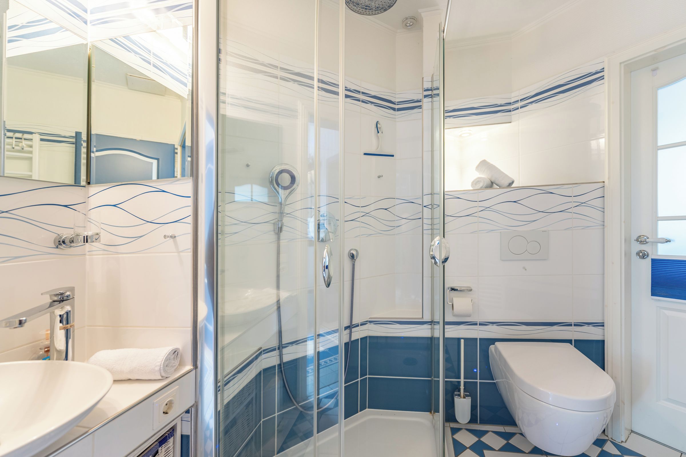Ein Badezimmer mit einer Duschkabine, einem weißen Waschbecken und einer Toilette.