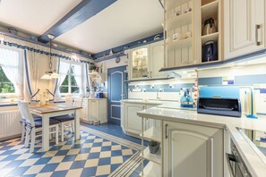 Une cuisine avec un carrelage à motifs, des meubles blancs et un coin repas comprenant une table et des chaises.