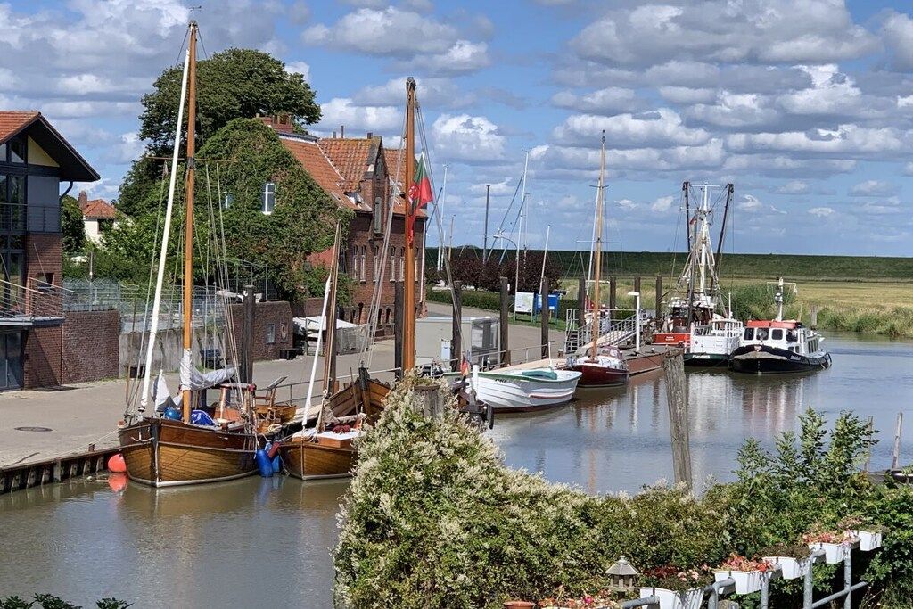 Un port de plaisance avec des bateaux amarrés, un bâtiment avec un toit rouge et un ciel dégagé.