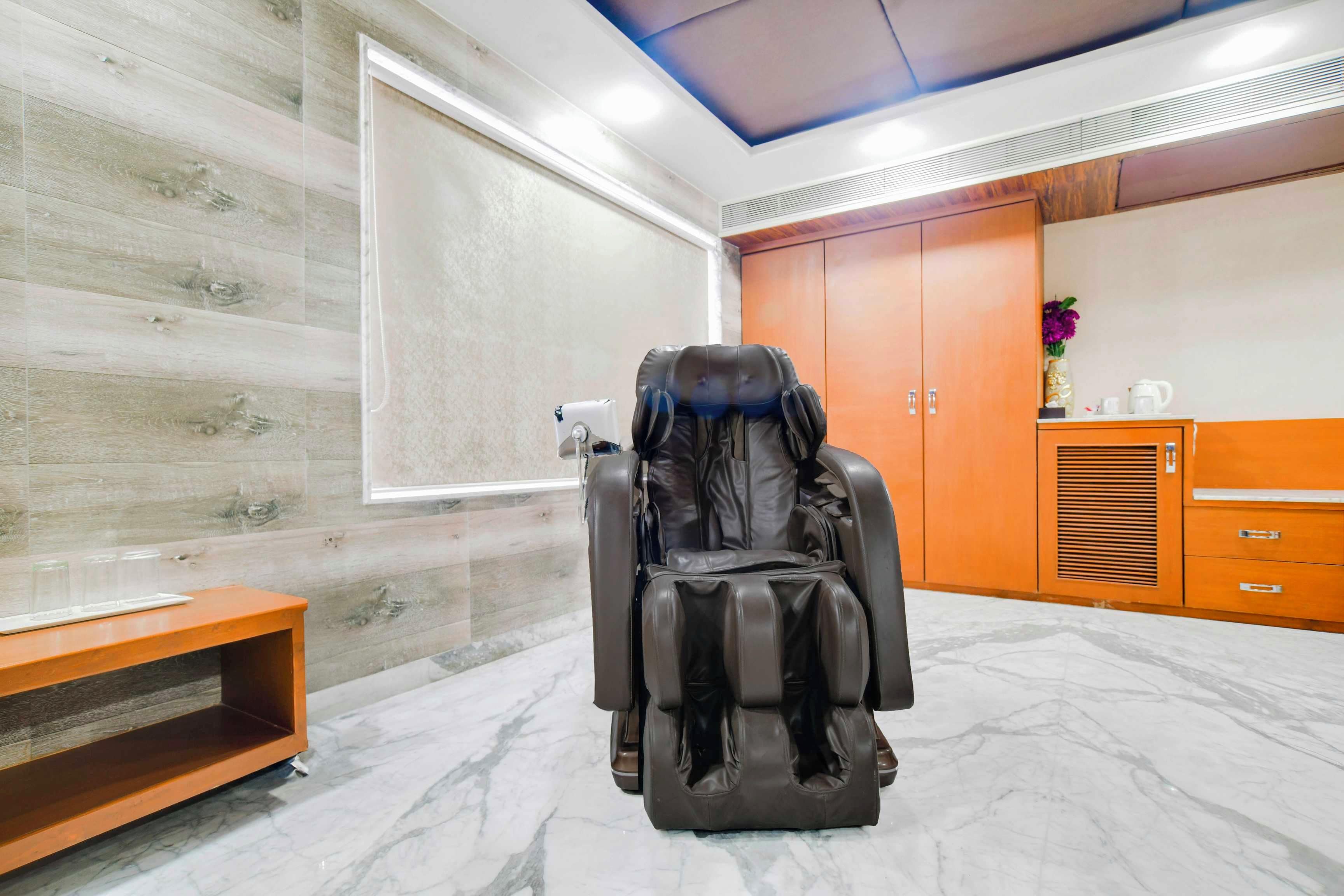 Una silla de masaje en una habitación con pared de madera, un armario y suelo de mármol.