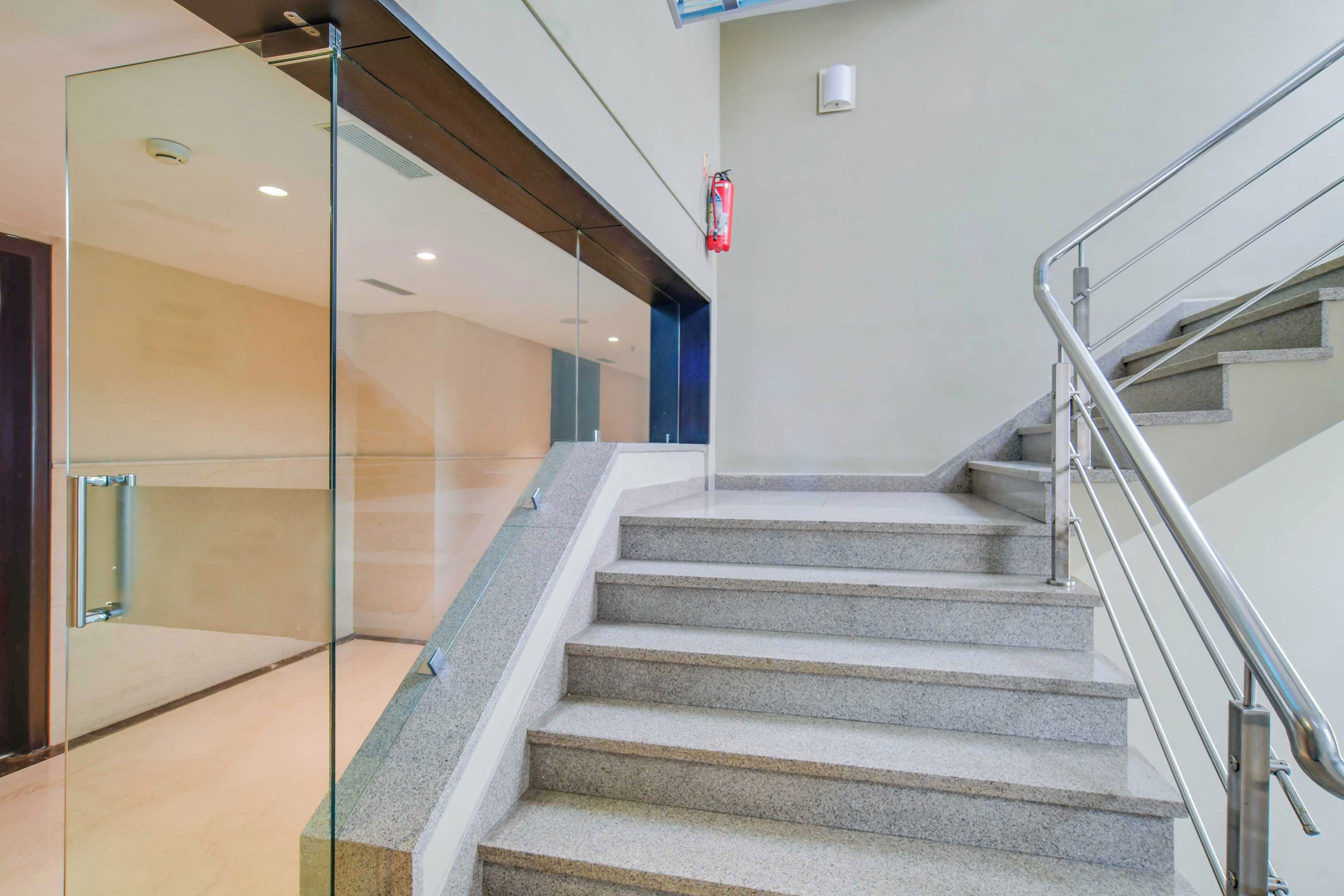 A staircase with a metal handrail and glass walls on one side.