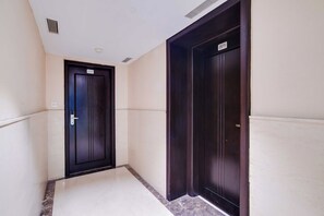 A corridor with two doors, one marked with the number 210, leading to a room. - Townhouse Oak Sapphire Star (Indore)