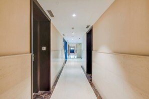 A hotel corridor with a marble floor, doors on either side, and a long hallway leading to a bright end. - Townhouse Oak Sapphire Star (Indore)