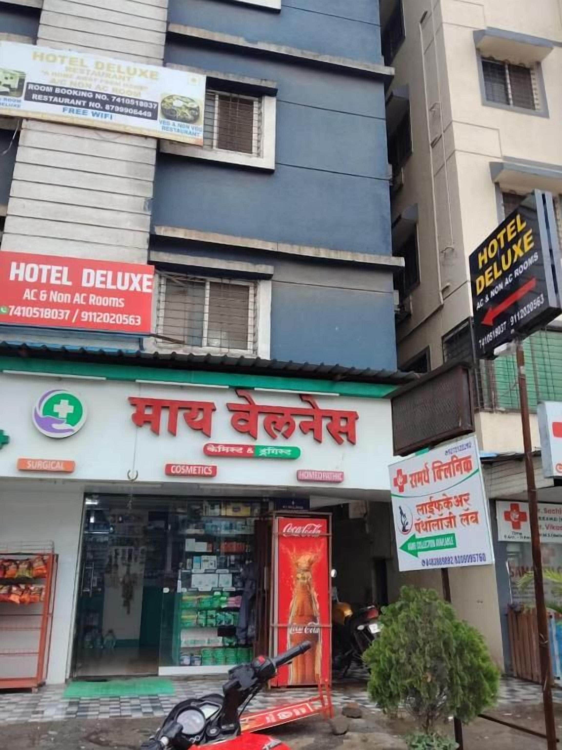 Un edificio con letreros que indican HOTEL DELUXE y MAY BHELNESA, señalando un hotel y una farmacia.