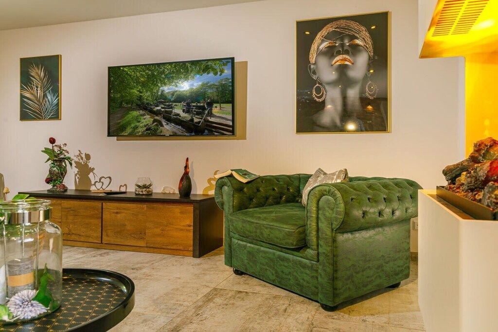 A living room with a green sofa, a flat-screen TV, and artwork on the wall.