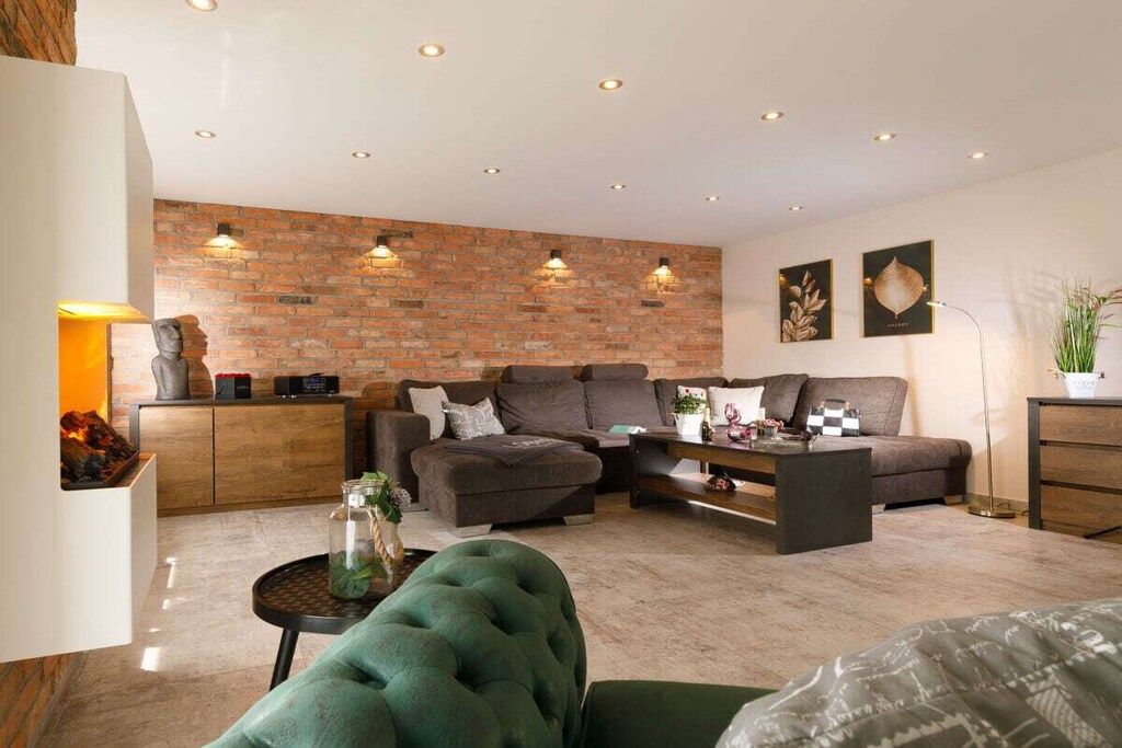 Ein modernes Wohnzimmer mit einer Ziegelfassade, zwei Sofas, einem Couchtisch und einem Kamin.