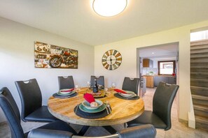A dining area with a round table set for six, surrounded by black chairs. A wall clock and a vintage motorcycle poster are visible. - Holiday home in Hasselfelde with barbecue (Hasselfelde)
