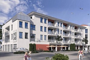 A multi-story residential building with balconies, a covered outdoor seating area, and a paved courtyard. - Sea lights Duhner Entrée 8 (Cuxhaven)