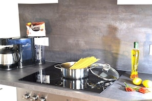 A kitchen with a stove, pots, a coffee maker, a bottle of oil, lemons, and a bag of coffee. - Sea lights Duhner Entrée 8 (Cuxhaven)