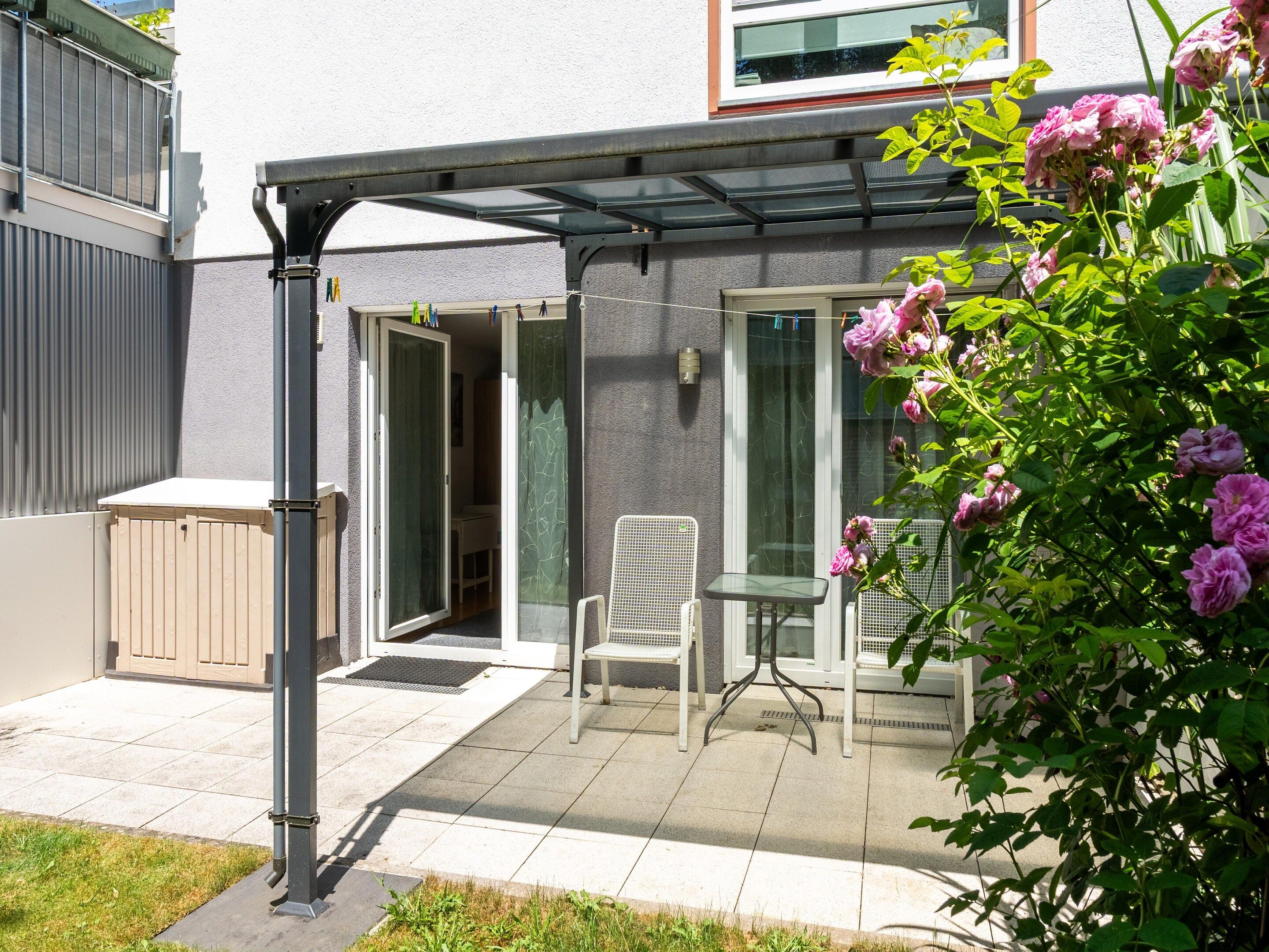 Ein Patio mit überdachter Sitzgruppe, einer Tür zu einem Zimmer und einem kleinen Tisch.