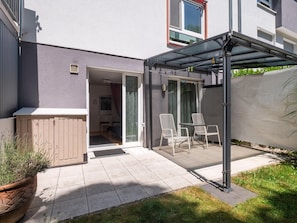 Eine Terrasse mit überdachter Sitzgruppe, einem Holzschrank und einem Blumentopf.