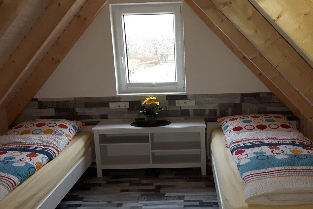 A small, cozy room with two beds, a window, and a small table with a plant.