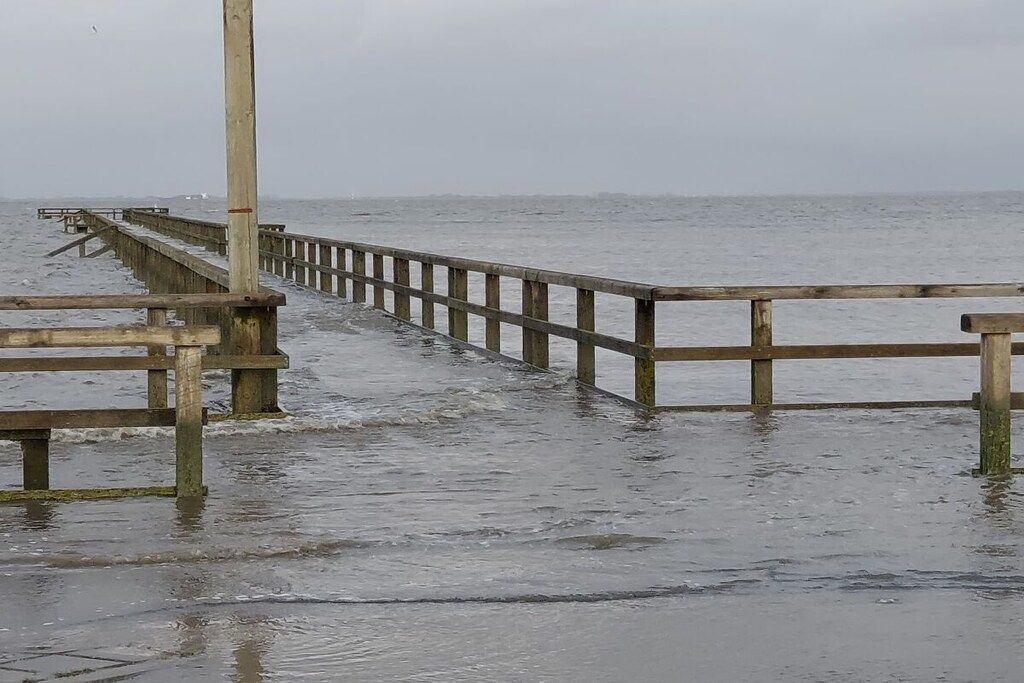 A wooden pier extending into a body of water with a cloudy sky above.