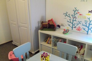 A child's playroom with a small house, a shelf with toys, and a wall decoration with fish and coral. - Holiday home in Juist with swimming pool (Juist)