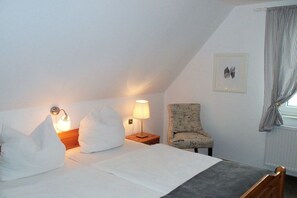 A bedroom with a bed, two bedside lamps, a chair, and a window with curtains. - Holiday home in Juist with swimming pool (Juist)