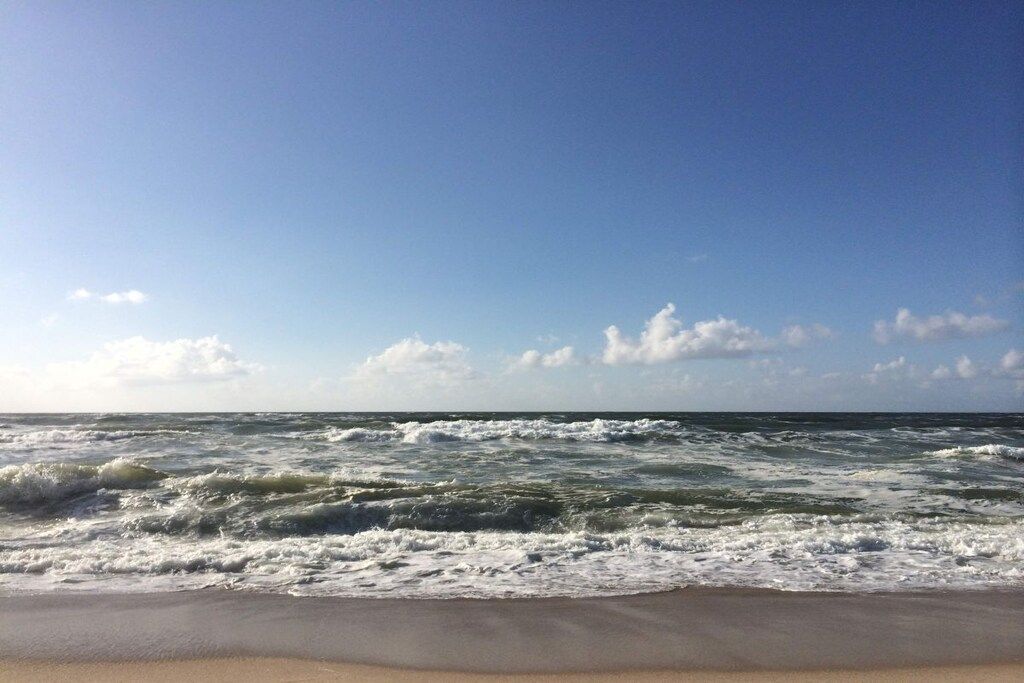 Ein Strand mit Wellen und blauem Himmel.