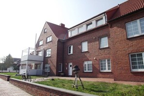 A brick building with a balcony and a chimney. - with loggia in Haus Wittdün (Juist)