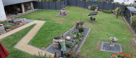 A residential backyard with a paved patio, a small garden area with plants and a bird bath, and a visible garage.