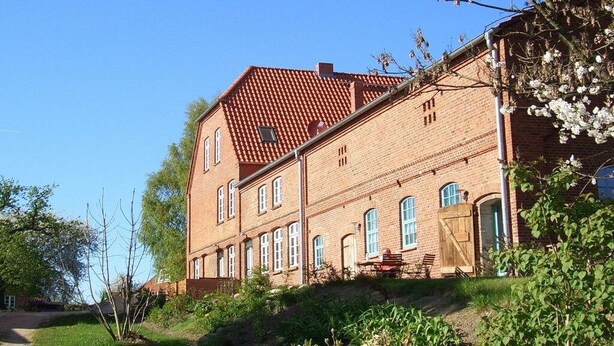 Ein Gebäude aus Backsteinen mit vielen Fenstern und einem roten Ziegeldach.