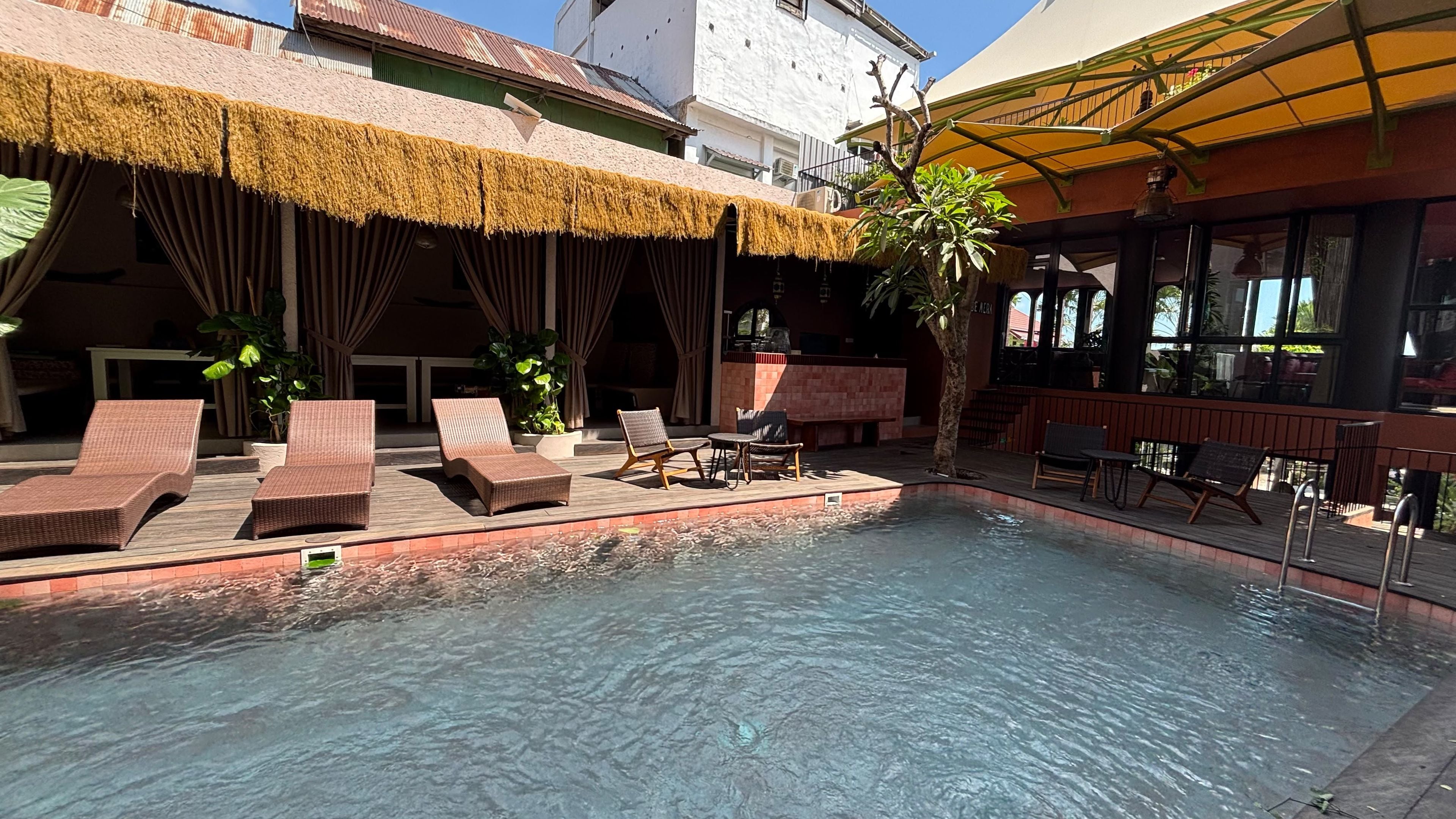 Zona de piscina con sillones de descanso y un bar.