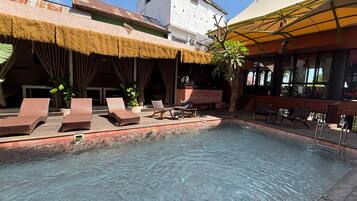 Zona de piscina con sillones de descanso y un bar.