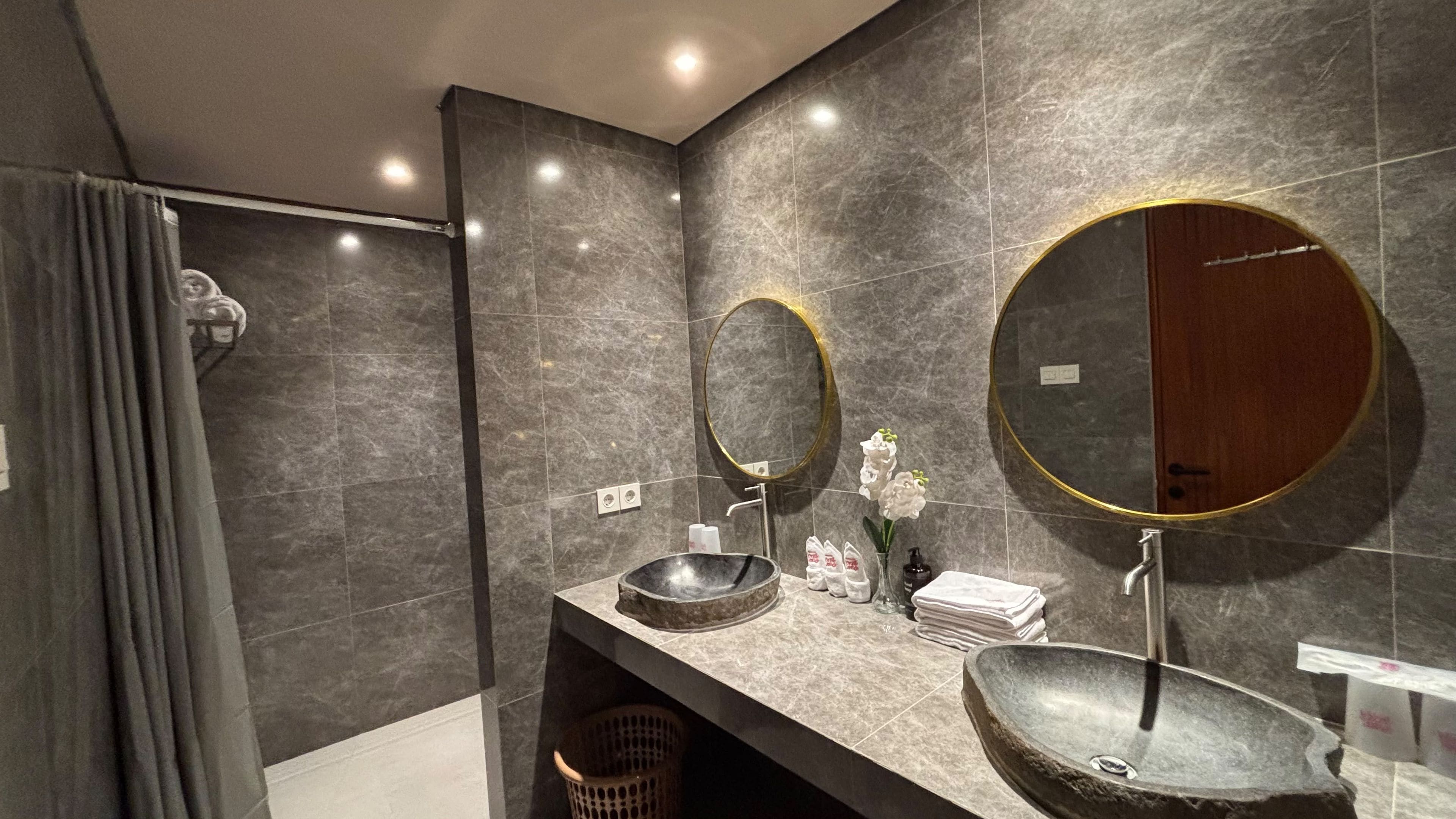 Un baño moderno con un espejo grande, dos lavamanos y zona de ducha.