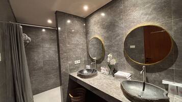 Un baño moderno con un espejo grande, dos lavamanos y zona de ducha.