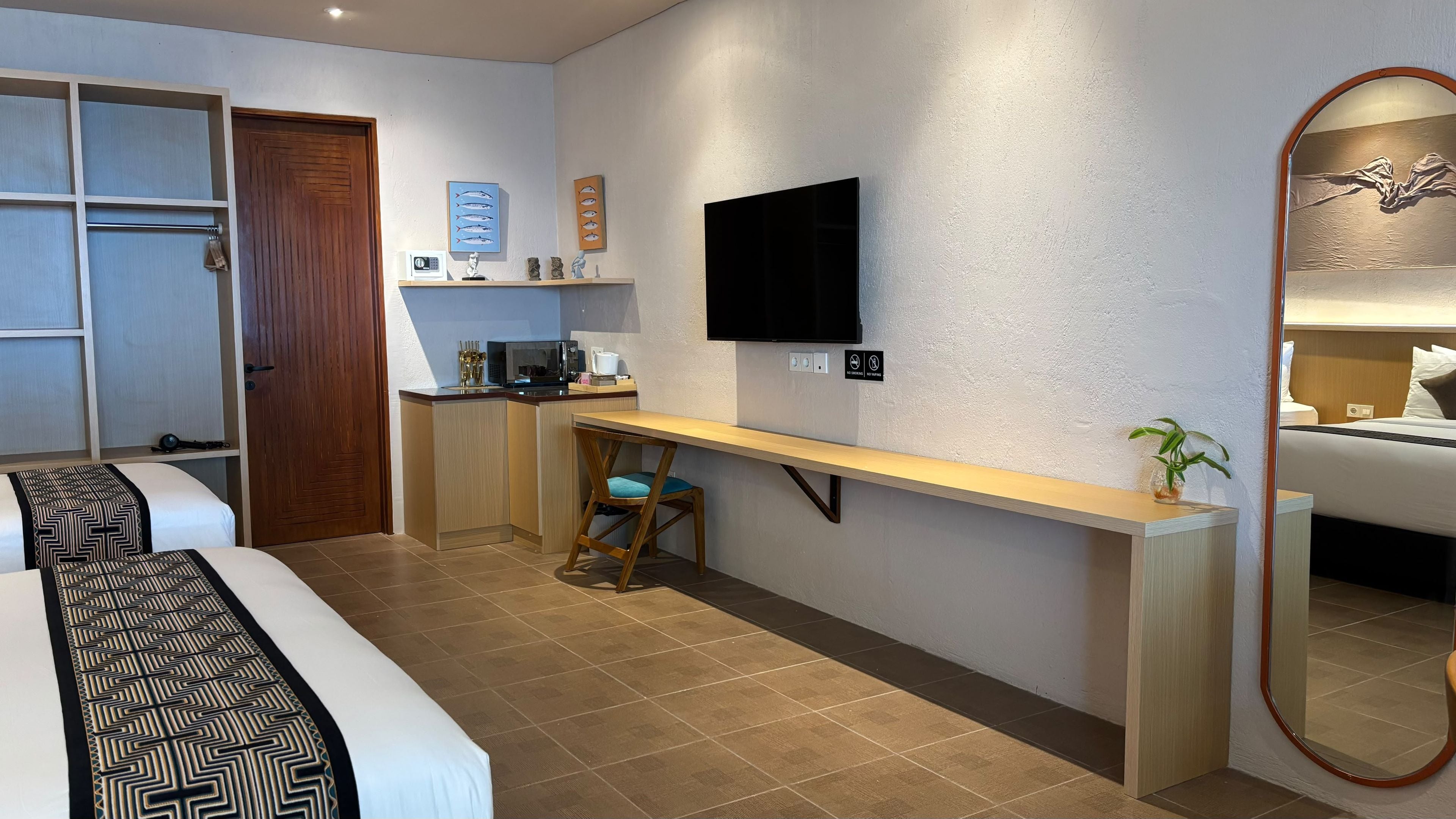 A compact hotel room with a bed, a desk, a chair, a TV, and a mirror.