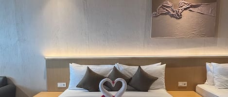 Habitación de hotel con una cama grande, cabecera con lámpara, obra de arte en la pared y mesita de noche con lámpara.