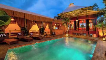 Área de piscina com espreguiçadeiras e bar.