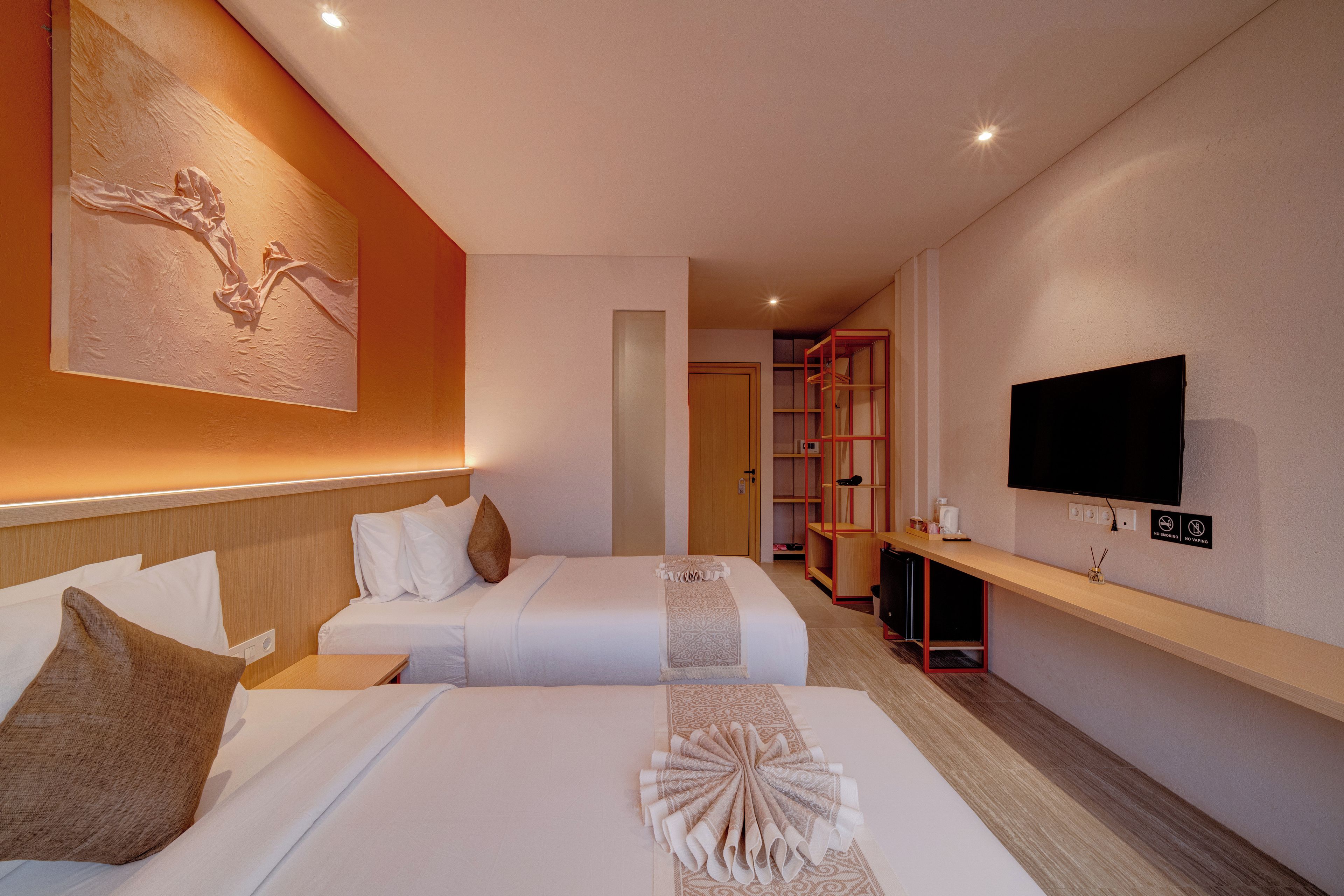 Ein Hotelzimmer mit zwei Betten, einem Fernseher, einem Bücherregal und einem Bild an der Wand.