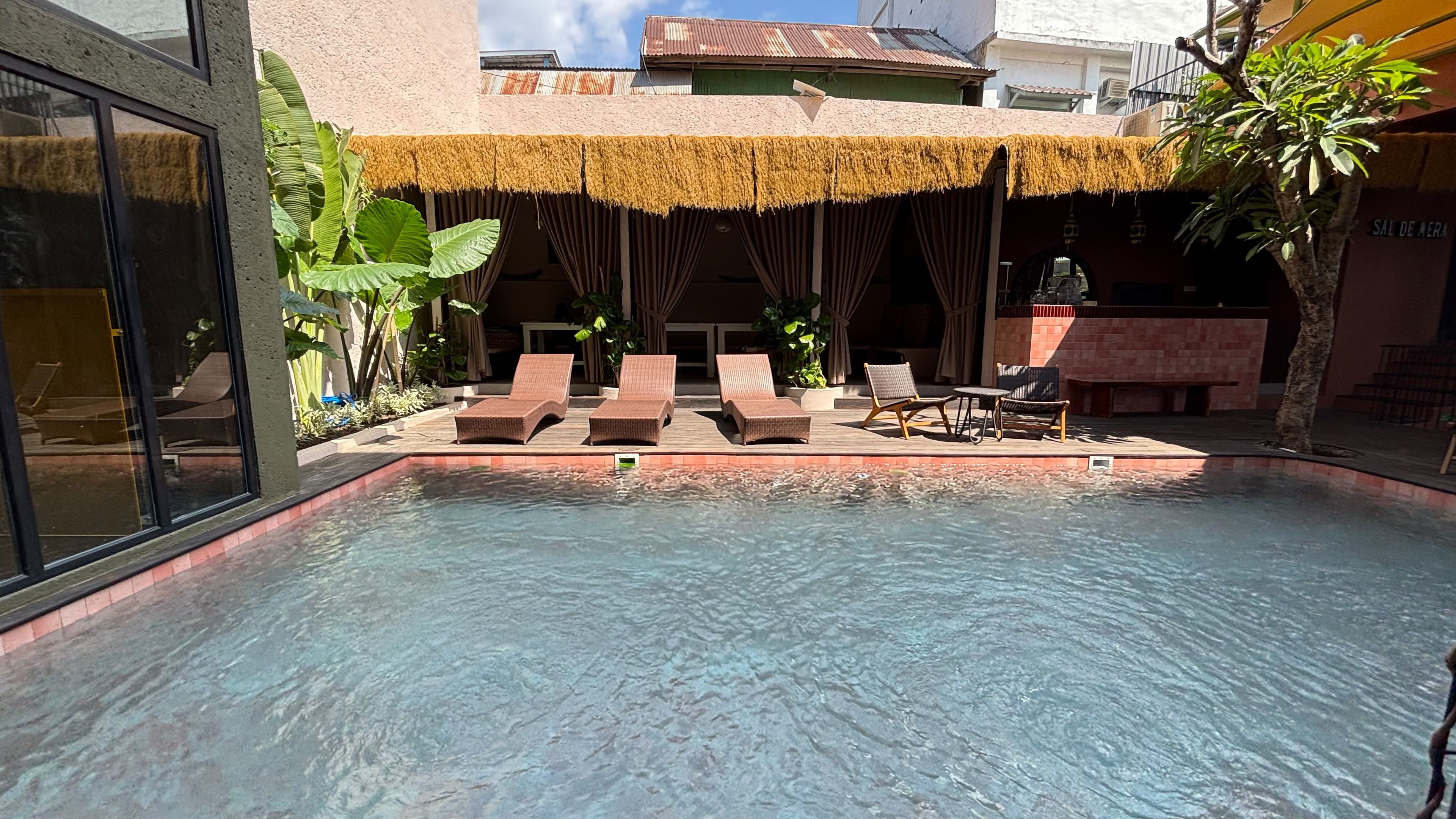 A swimming pool with lounge chairs and a thatched roof structure.
