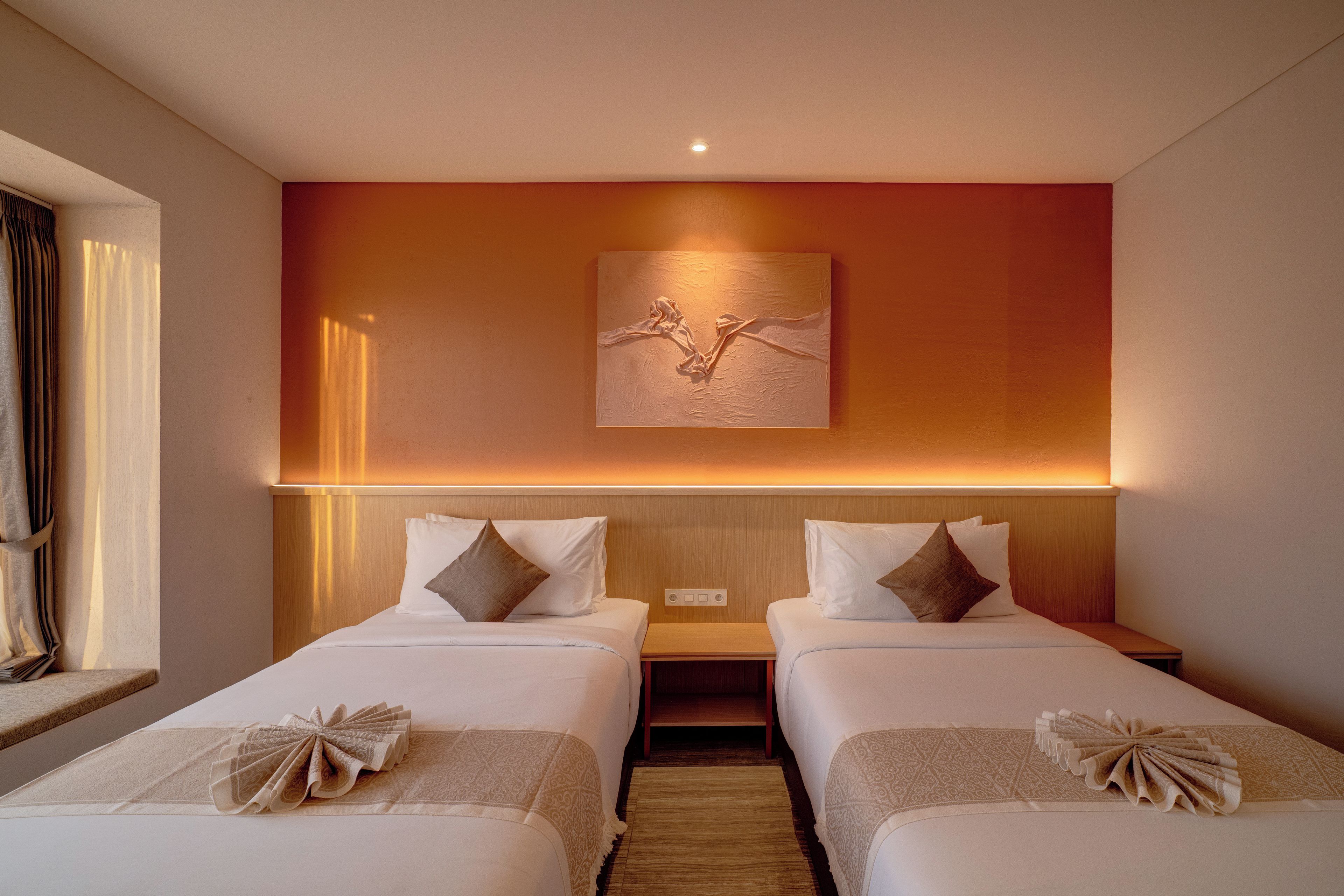 A hotel room with two beds, a wall-mounted artwork, and a bedside table.