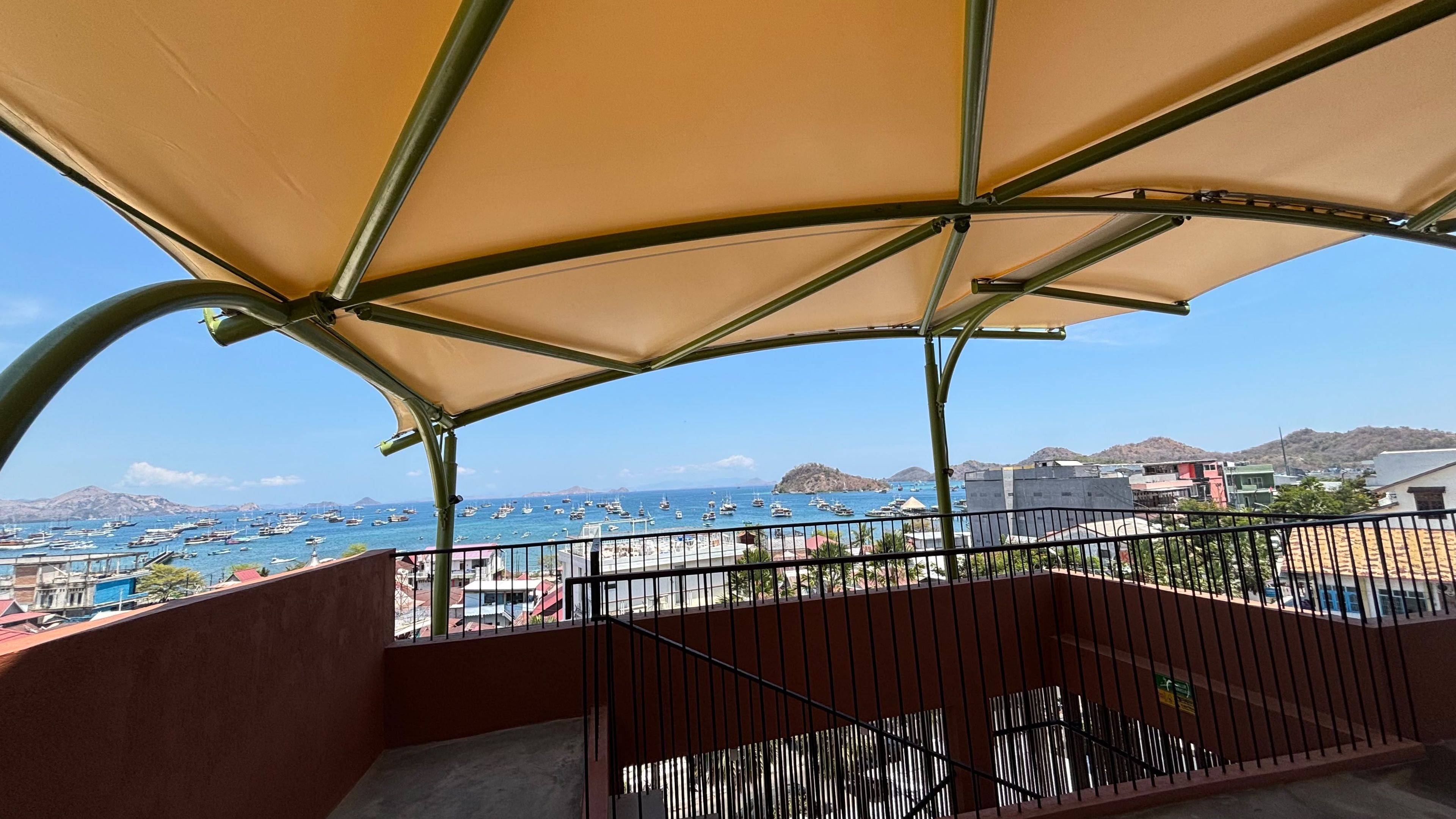 A balcony with a view of a marina and distant hills.