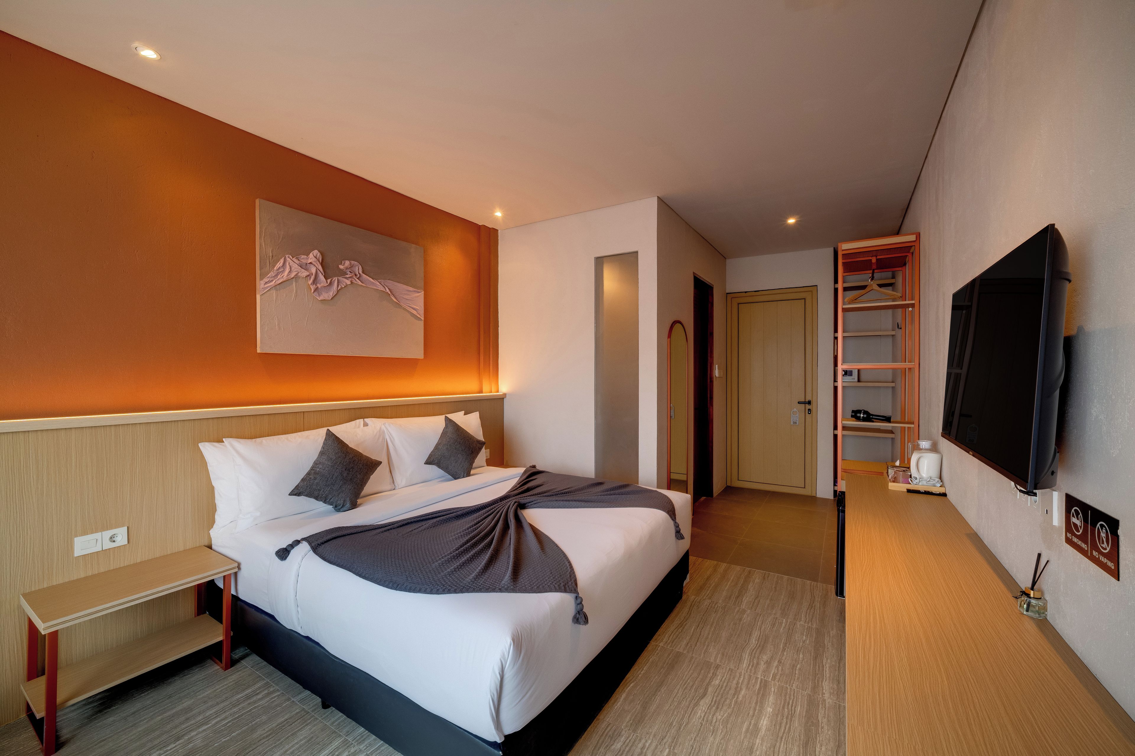 Une chambre d’hôtel avec un lit, une table de chevet et un téléviseur fixé au mur.