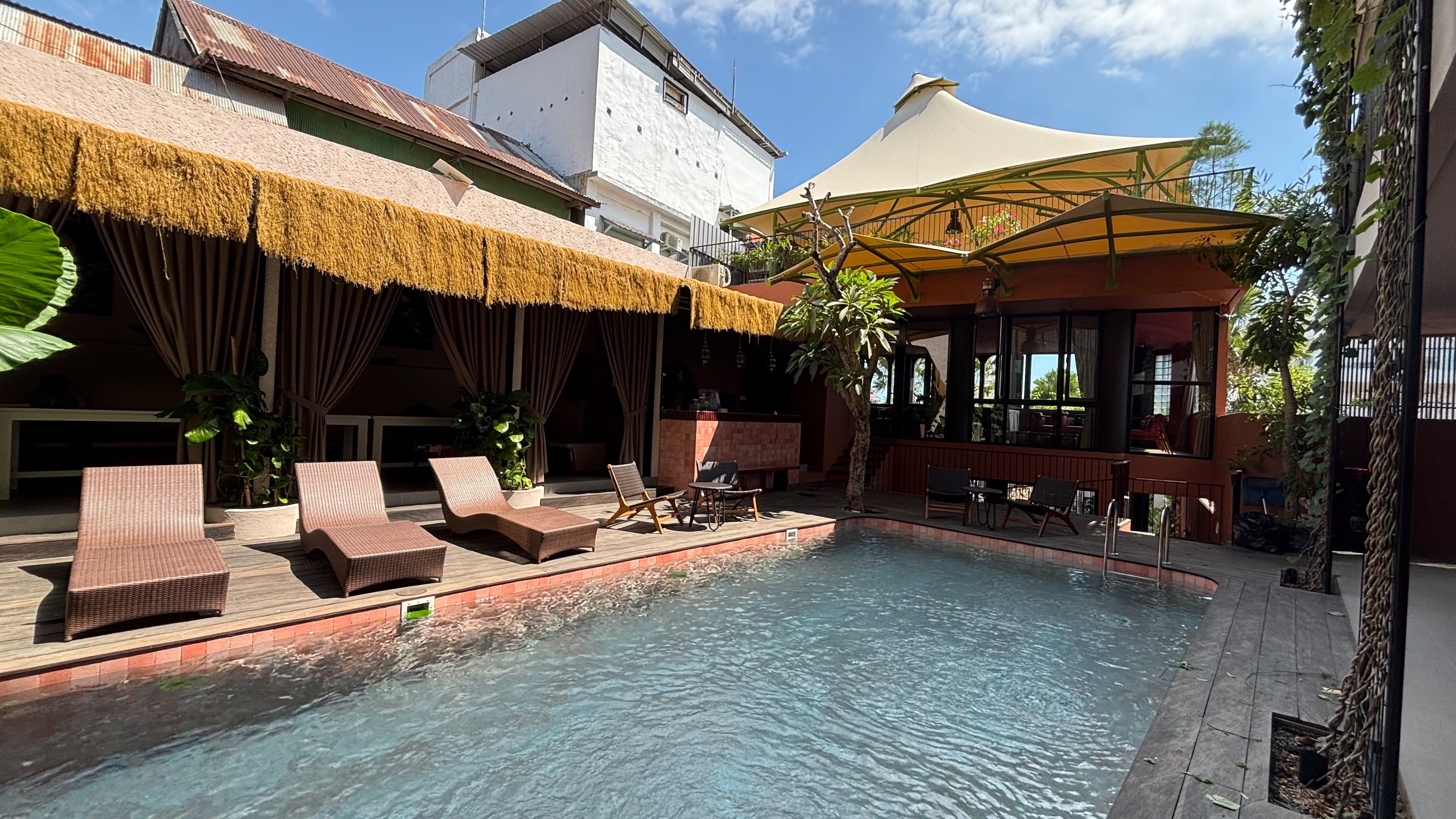 A pool area with lounge chairs and a thatched roof structure.