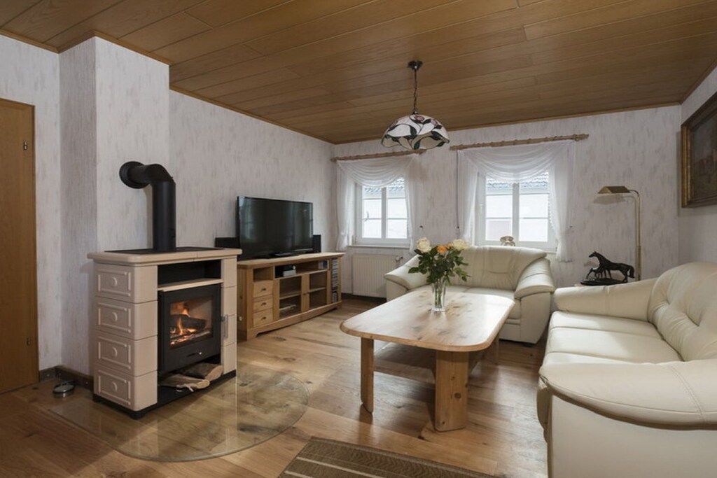 Een woonkamer met een open haard, televisie, bank en een tafel met een bloevas.
