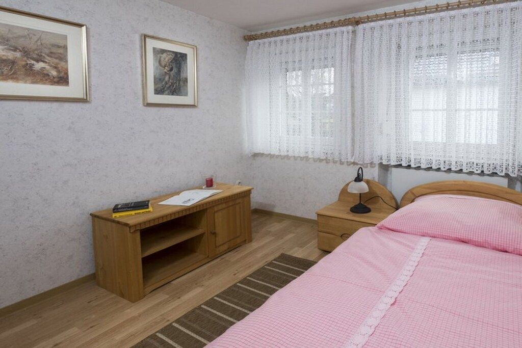 Une chambre à coucher avec un lit, une table de chevet en bois, un bureau et deux tableaux encadrés accrochés au mur.