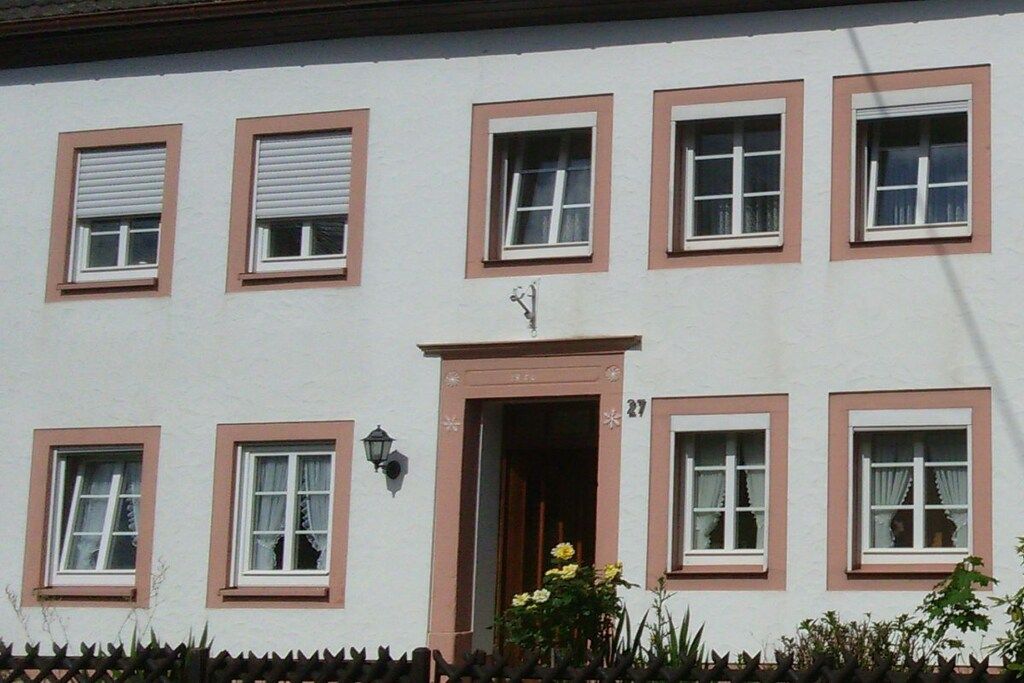 A building with multiple windows, some with shutters, and a door with a number above it.