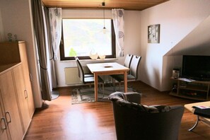 Ein kompakter Wohnbereich mit Essplatz, Fernseher und Heizkörper.