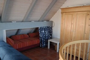 A loft bedroom with a bunk bed, a small table, and a wooden wardrobe. - Maisonette apartment at Tief (Dornum)