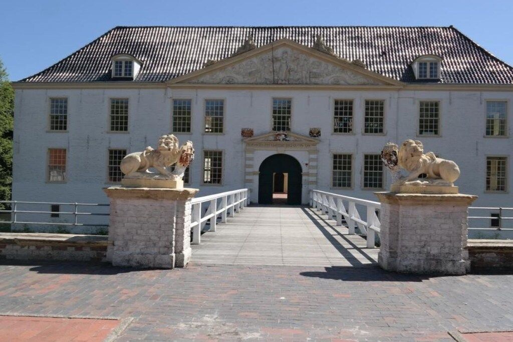 A building with a symmetrical facade, a central entrance, and two statues on either side.