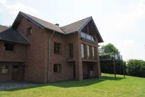 A two-story brick house with a sloped roof, a balcony, and a covered outdoor seating area. - Holiday apartment in Daun with swimming pool (Daun)
