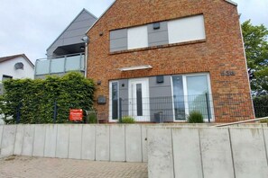 Een modern, tweelaags gebouw met een bakstenen gevel, grote ramen en een duidelijke ingang.