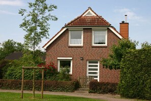 A two-story brick house with a red-tiled roof, a front door, and a small porch area. - Holiday home in Cuxhaven with swimming pool (Cuxhaven)