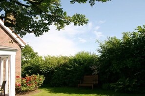 A brick house with a garden, a bench, and a tree. - Holiday home in Cuxhaven with swimming pool (Cuxhaven)