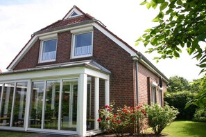 A two-story house with a conservatory, brick exterior, and a small balcony. - Holiday home in Cuxhaven with swimming pool (Cuxhaven)