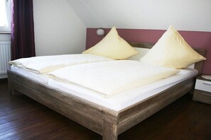 A single bed with a wooden frame, two pillows, and a bedside table with a lamp. - Holiday home in Cuxhaven with swimming pool (Cuxhaven)