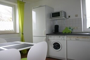 A compact kitchen with a refrigerator, microwave, and washing machine. - Holiday home in Cuxhaven with swimming pool (Cuxhaven)