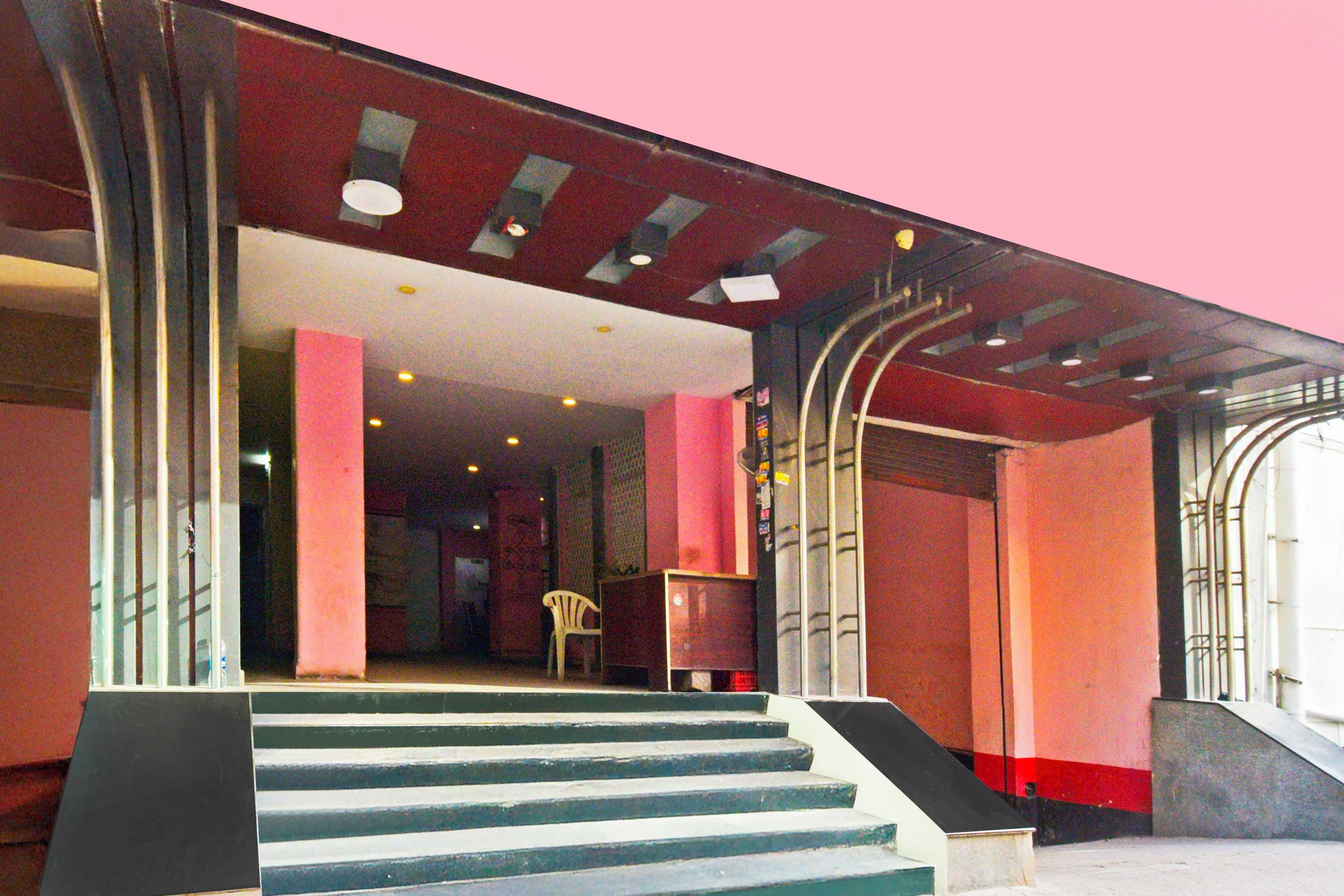 Una escalera conduce a un espacio interior con una decoración en rojo y blanco, columnas y una silla.